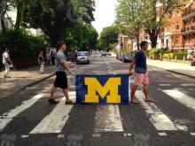 Two students carrying a michigan flag across a crosswalk