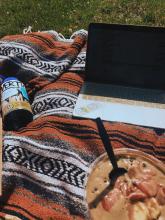 soup, water bottle, and a laptop on a blanket